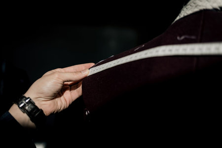 modern tailor measuring back length of bespoke suit during model fitting in atelier studio