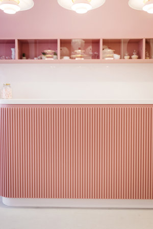 Stylish pink kitchen interior with dining table and lampsの写真素材