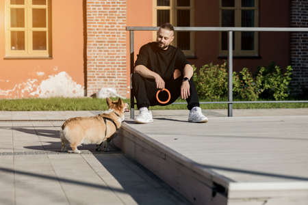 handsome man in black casual clothes with a dog near a brick buildingの写真素材