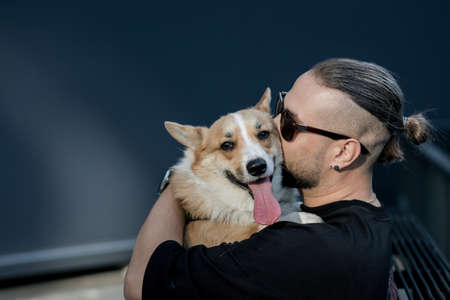 handsome man in black casual clothes with a dog near a brick buildingの写真素材