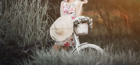 Beautiful woman in dress riding on bike in park. eco-friendly mode of transportの写真素材