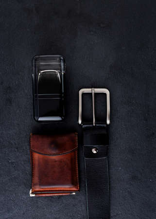Fashionable men's black belt made of genuine leather with a light metal buckle on a dark background.の写真素材