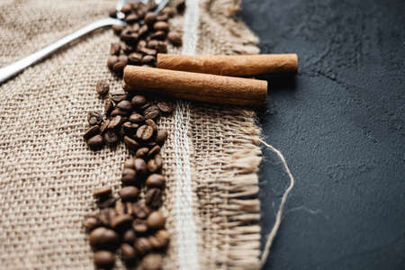 Roasted arabica coffee beans, cinnamon sticks on a dark wooden background,top view. selective focusの写真素材
