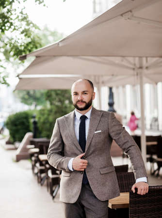 serious businessman standing in the city, looking away, having a confident look. caucasian bearded man in suitの写真素材
