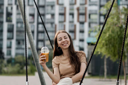 Beautiful smiling girl drinking a plastic glass of orange juice. relaxation conceptの写真素材