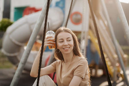 Beautiful smiling girl drinking a plastic glass of orange juice. relaxation conceptの写真素材