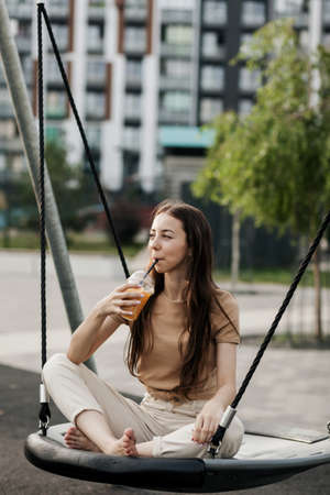 Beautiful smiling girl drinking a plastic glass of orange juice. relaxation conceptの写真素材