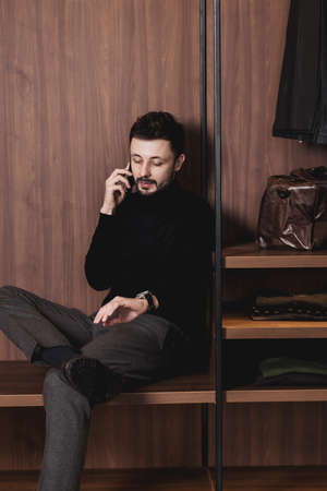 Attractive smart young man sitting on in the living room, using mobile phone. communicationの写真素材