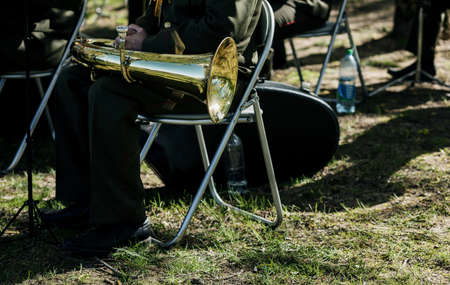 trombone player from a brass orchestra sitting on chair outdoorsの写真素材
