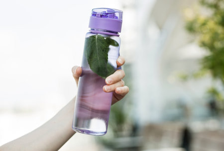 woman holding in hand bottle of water detox with mint. thirst. refreshing drink