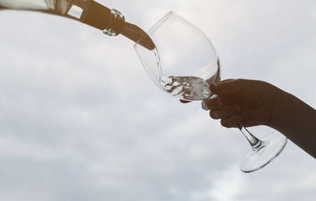 Pouring champagne into glass. Pouring sparkling wine from bottleの写真素材