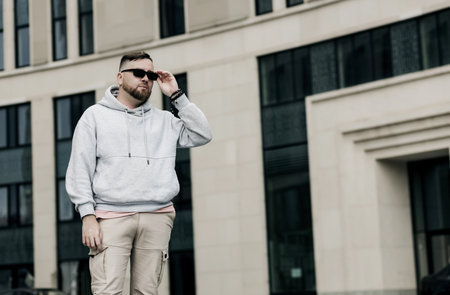 handsome hipster man in sunglasses with beard wearing gray blank hoodie or sweatshirtの写真素材