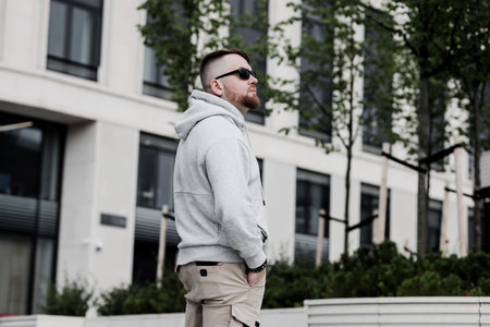 handsome hipster man in sunglasses with beard wearing gray blank hoodie or sweatshirtの写真素材
