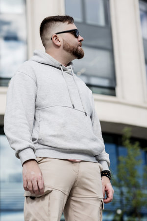 handsome hipster man in sunglasses with beard wearing gray blank hoodie or sweatshirtの写真素材