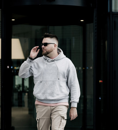 handsome hipster man in sunglasses with beard wearing gray blank hoodie or sweatshirtの写真素材