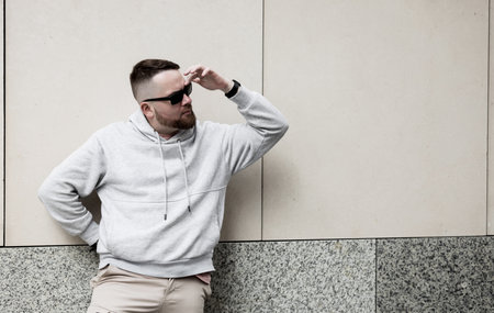 handsome hipster man in sunglasses with beard wearing gray blank hoodie or sweatshirtの写真素材