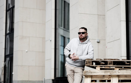 Urban bearded man wearing stylish gray hoodie and sunglassesの写真素材