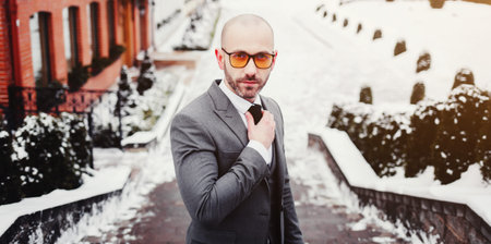 young guy with a beard with glasses in a suit posing on the streetの写真素材