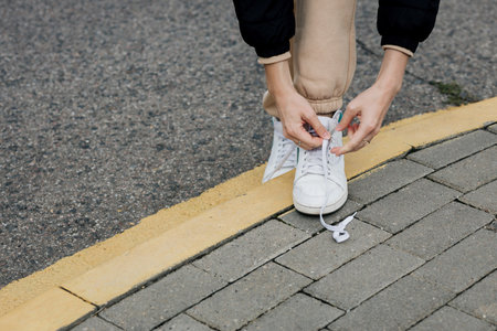 Hands of a young woman lacing white sneakers.の写真素材