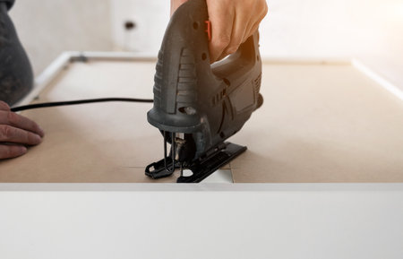 Man use electric jigsaw. Carpenter is engaged in woodworking. furniture worker.の写真素材