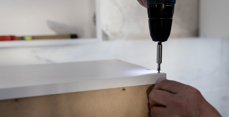 Assembling furniture from chipboar. laborer using a cordless screwdriverの写真素材