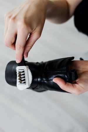 Hands cleaning women's shoe (boot) with a brush. Footwear maintenanceの写真素材