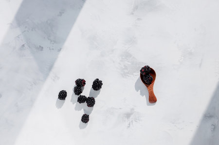 Spoon of ripe blackberries on white wooden backgroundの写真素材