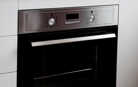New electric oven in kitchen. Built-In Fan Oven. Stainless Steel Body with Black Glass Transparent Doorsの写真素材