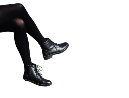 sexy female legs in black pantyhose and shoes isolated on white background. a girl is sitting on black rough bootsの写真素材