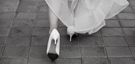 close-up of female heels of a bride in a wedding dress walking on the sidewalk. black and whiteの写真素材