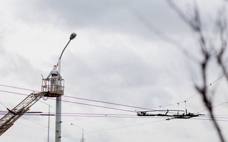 worker in a cradle on a lamppost. electrician is working on a fieldの写真素材