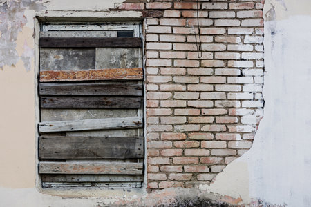 Boarded-up window in an abandoned old building. rustic brick house on the streetの写真素材