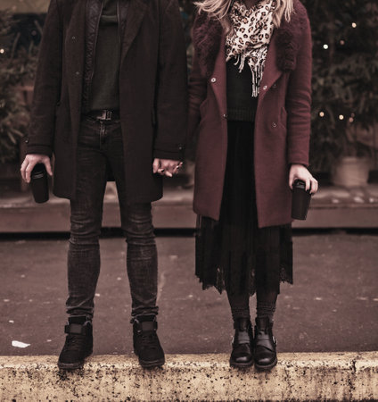 Beautiful young woman and man holding coffee while standing in the street. happy coupleの写真素材