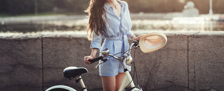 Cheerful woman with hat near bicycle in sunset. lady riding bike. lifestyle conceptの写真素材