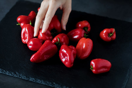 mini sweet peppers on table. the hand takes the red pepper from the blackboardの写真素材