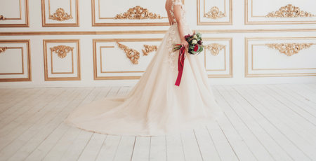 Beautiful bride in wedding dress with bouquet in classic interior.の写真素材