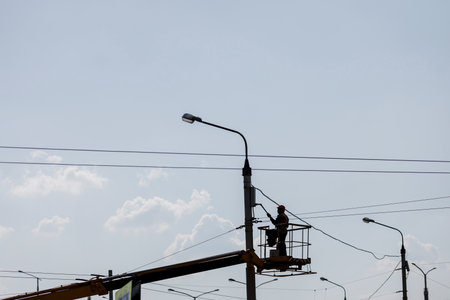 Man on lifting platform. silhouette of a worker painting a lamppostの写真素材