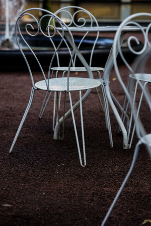 Victorian style white empty metal chairs and tables in outdoor cafe. Wrought iron furniture, old fashion cozy cafe terrace,の写真素材