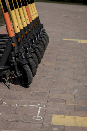 Electric urban transportation: the row of electric readies to ride scooter bikes with accumulators in the center of a city on the pavementの写真素材