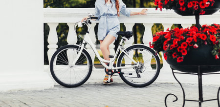 Charming woman with a bicycle near the bright flowers in the cityの写真素材