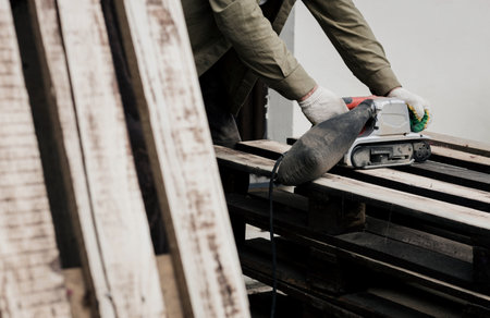 Man sanding wood with sander in a workshop. worker with belt sanderの写真素材