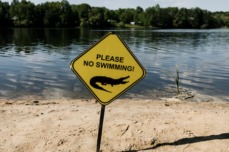 No swimming sign against the waves of lake. careful crocodilesの写真素材