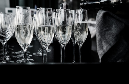 waiter pours wine and champagne into the glasses. Pouring sparkling wine