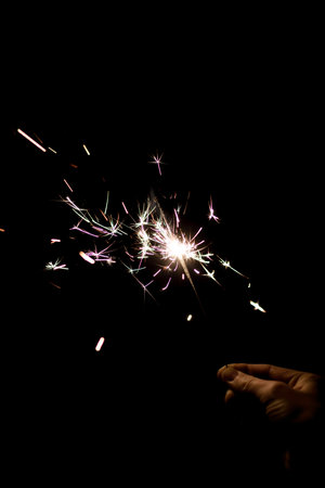 Female hand holding a burning sparkler. birthday or new year conceptの写真素材