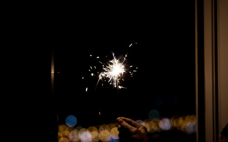 Hand holding a burning sparkler against blurred background
