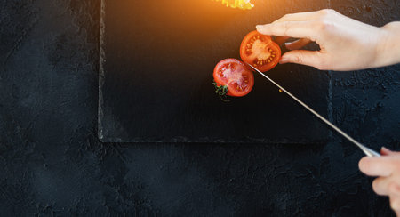 half-cut red tomato. close-up of a hand slicing vegetables. healthy food for vegans