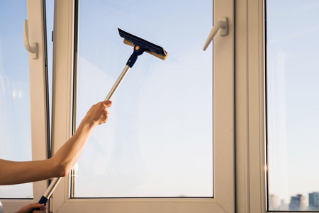 Window cleaner using mop to wash a window with clear blue skyの写真素材