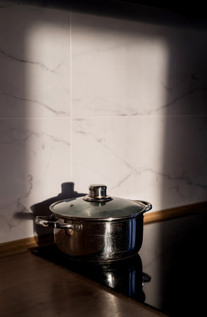 A steel saucepan stands on induction stove at sunset. Pot in modern kitchenの写真素材