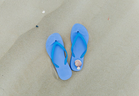 Women's rubber flip-flops stand on beautiful sand. The concept of recreation in hot countries.の写真素材