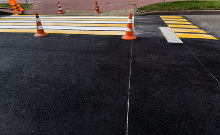 Work to update the pedestrian crossing markings on a summer day.